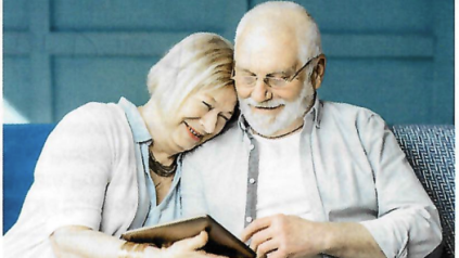 Older couple sitting on couch looking a tablet